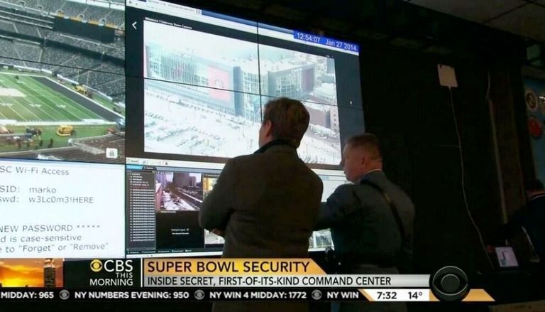 The Super Bowl command centre. Two men look at a screen. One is displaying the wifi access credentials.