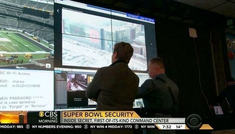 The Super Bowl command centre. Two men look at a screen. One is displaying the wifi access credentials.